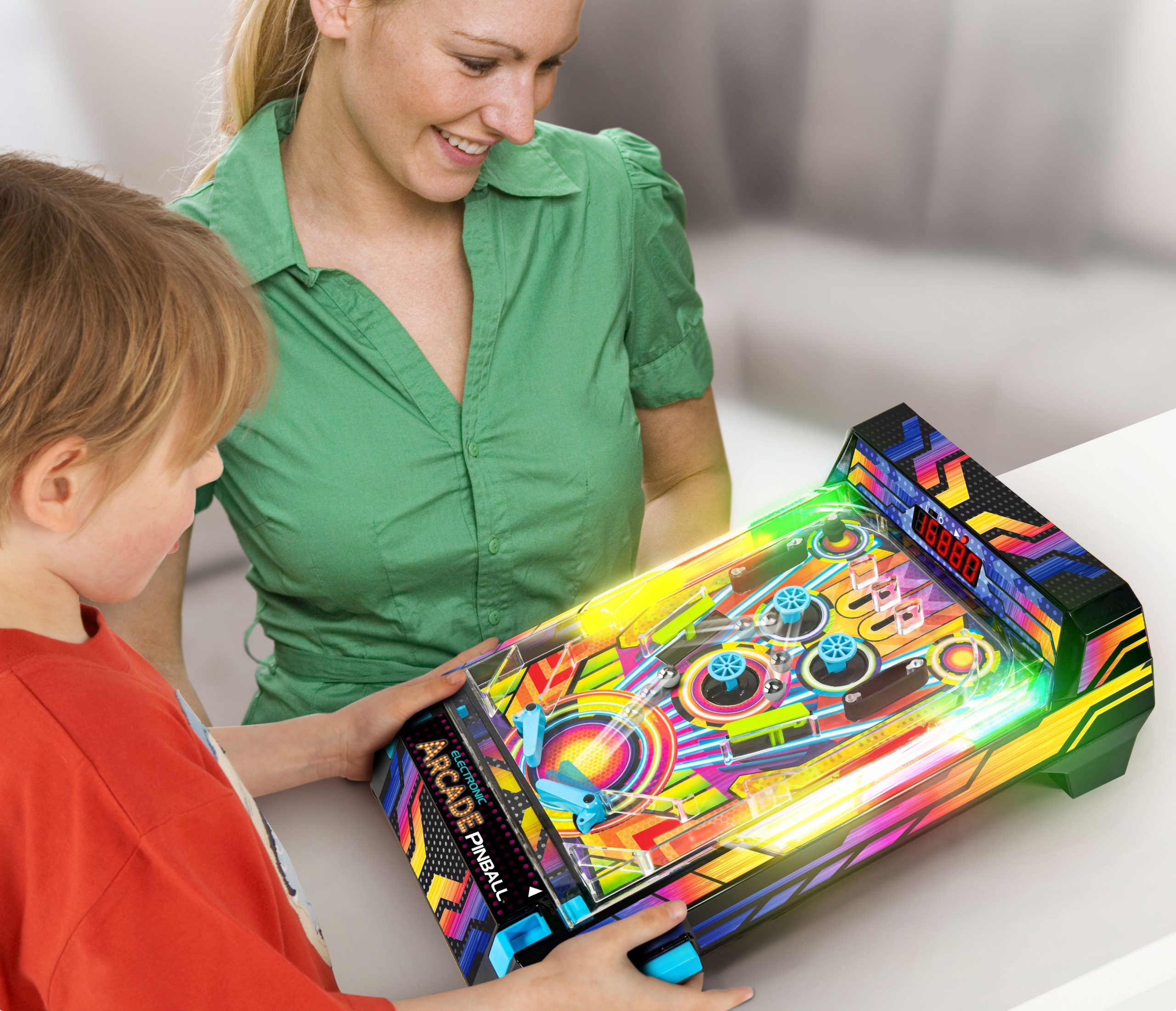 A boy and a girl play at a table with a pinball game